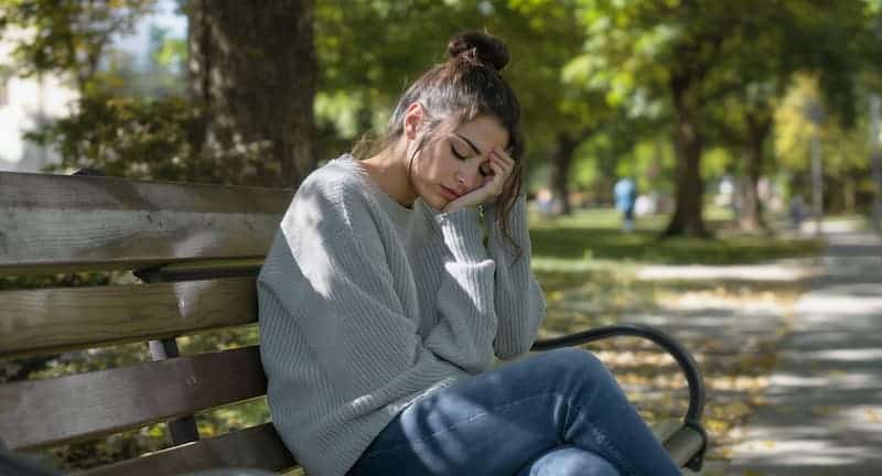 A young woman sits on a park bench, resting her head on her hand with a tired expression. The image symbolizes the frustration and wasted time Excel users experience while waiting for slow VLOOKUP operations to finish. Ideal for illustrating the inefficiency of manual data merging in spreadsheets and promoting faster, automated alternatives like Python a woman is tired